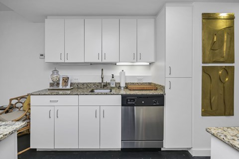 A kitchen with white cabinets and a granite countertop.