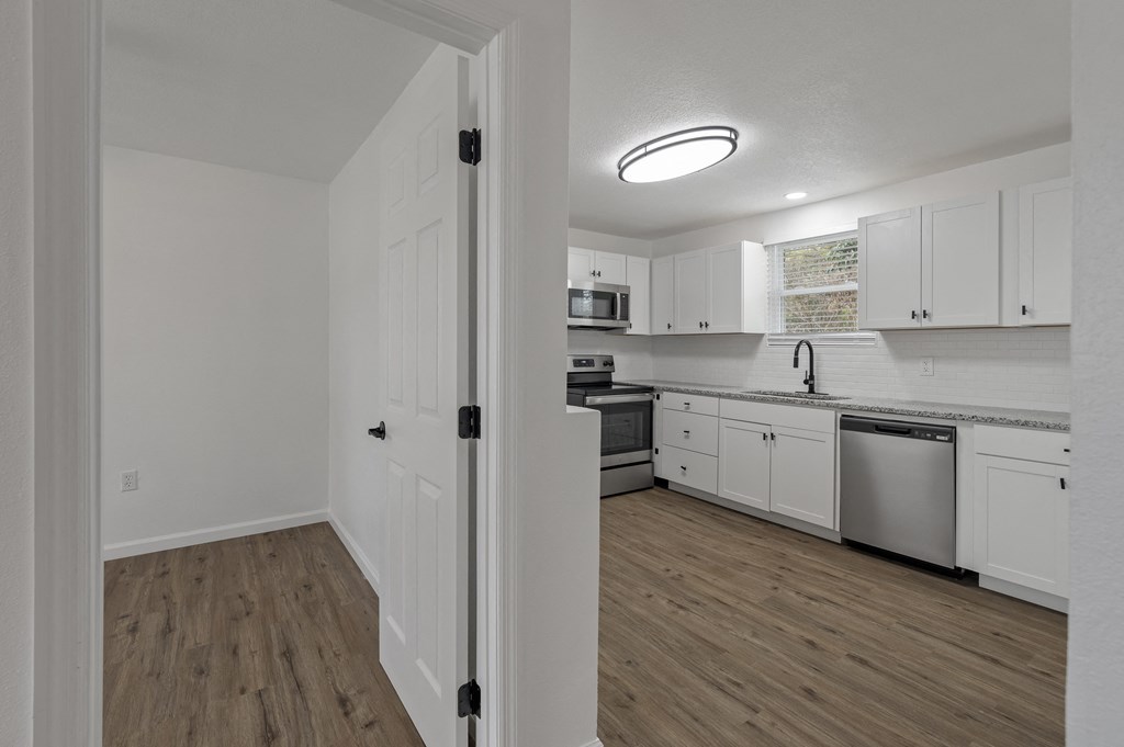 an empty kitchen with white cabinets and stainless steel appliances