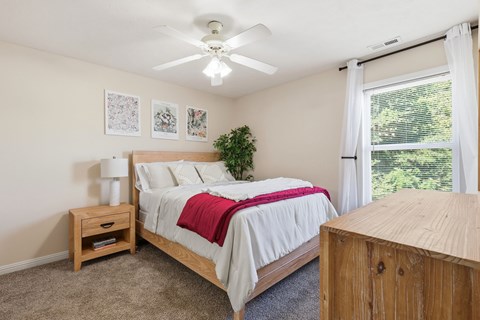 A bedroom with a bed, nightstand, and window.