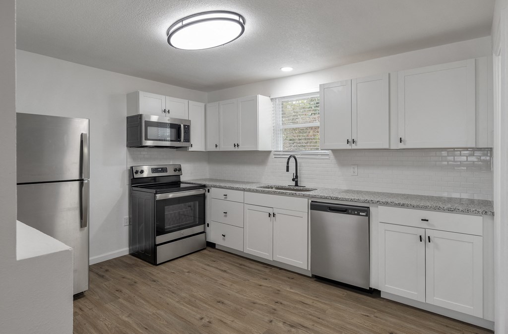 an empty kitchen with white cabinets and stainless steel appliances