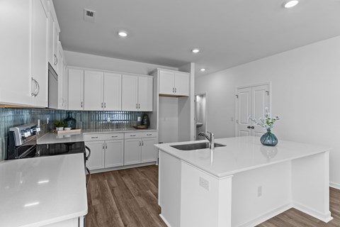 A modern kitchen with white cabinets and a large island.