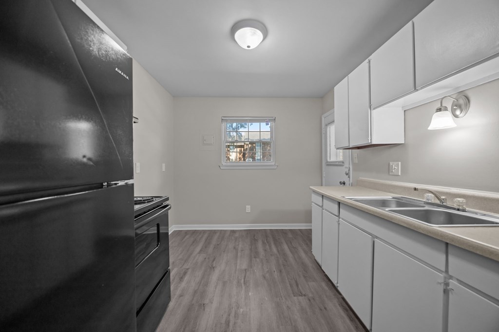 A kitchen with a black refrigerator and white cabinets.