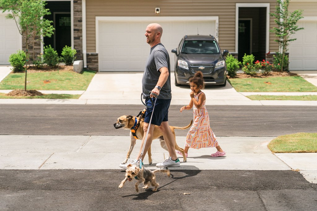 a man walking two dogs with a little girl behind him