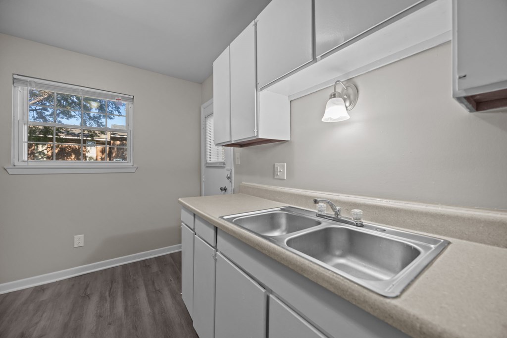 A kitchen with a window overlooking a tree-filled street.