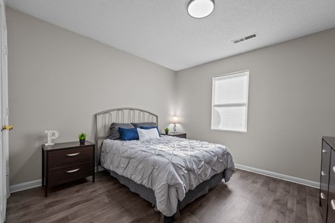 A bedroom with a bed, nightstand, and window.