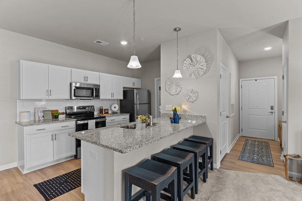 A kitchen with a granite countertop and bar stools.
