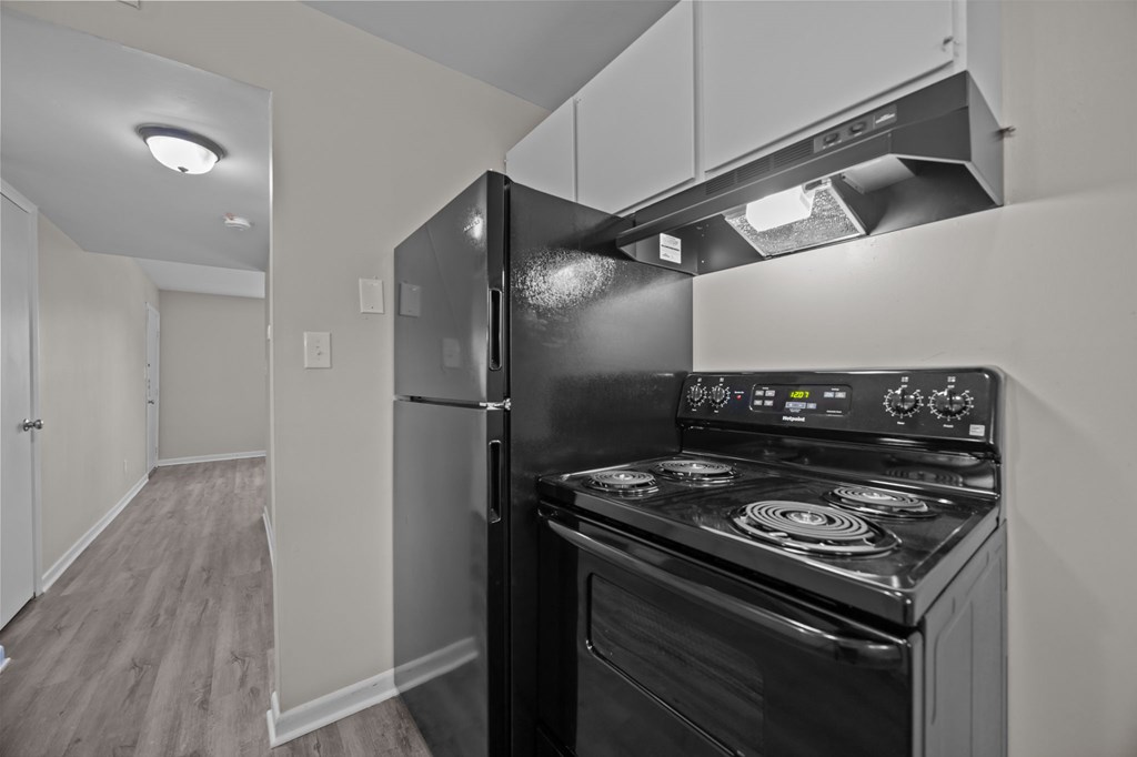 A black stove and refrigerator in a kitchen.