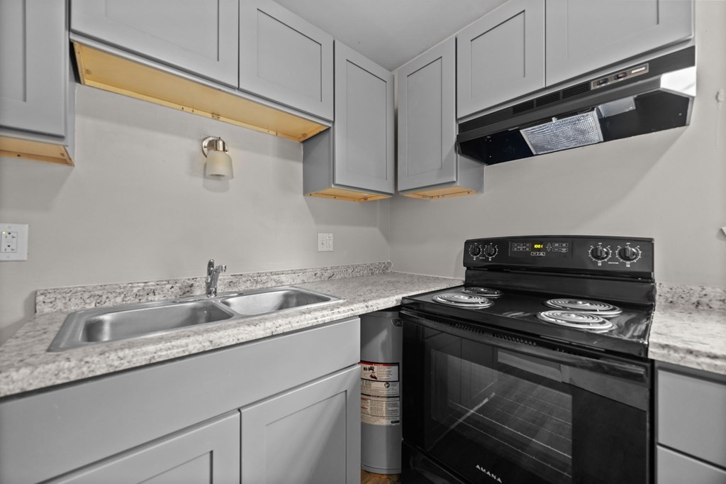 A black oven is on a kitchen counter with a sink and cabinets.