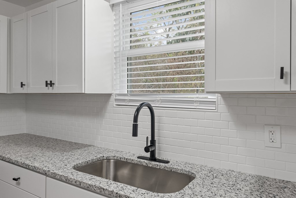a kitchen with white cabinets and a sink and a window