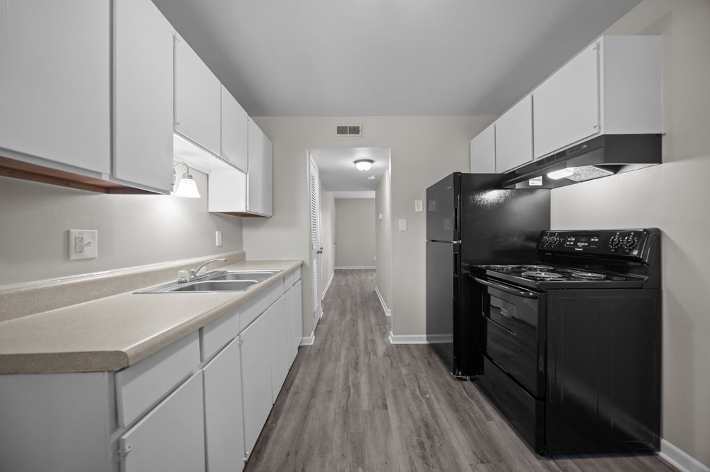 A black stove in a white kitchen with wood flooring.