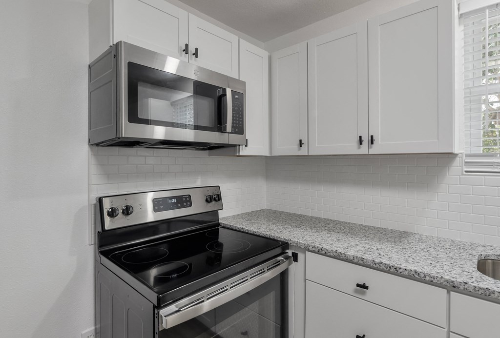 a kitchen with white cabinets and a stove and a microwave