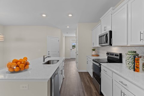 A kitchen with white cabinets and a countertop with oranges on it.