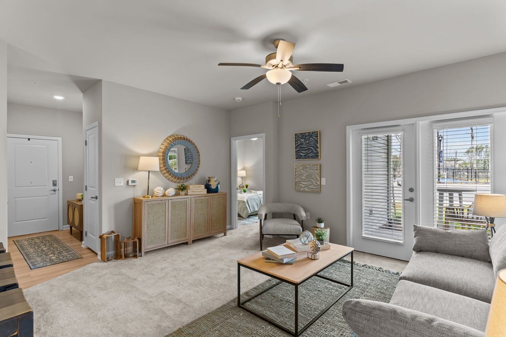 A living room with a grey couch, a coffee table, and a ceiling fan.