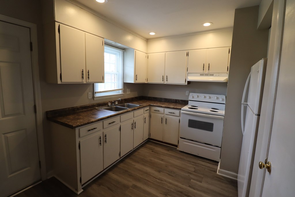 A kitchen with white cabinets and a brown countertop.