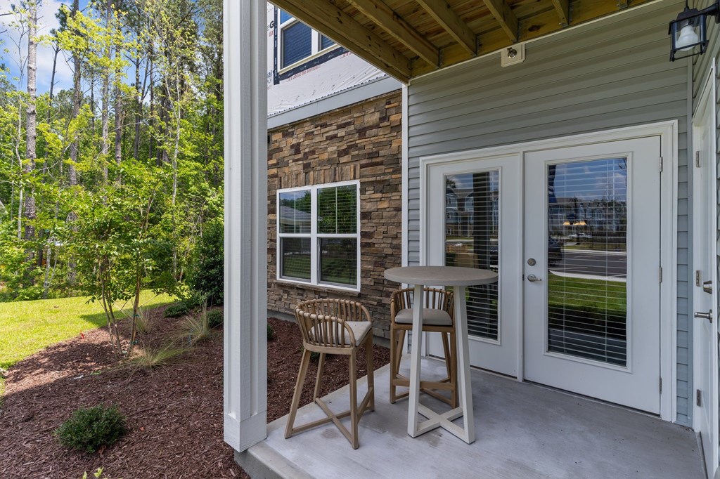 A patio with a table and chairs is on the front porch of a house.