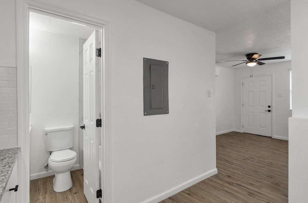 an open bathroom and living room with a toilet and a ceiling fan