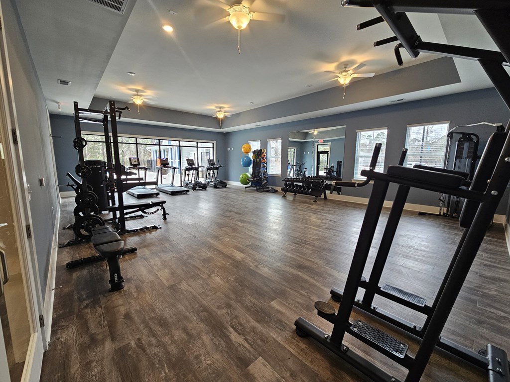 A gym with a variety of equipment including treadmills, weights, and exercise machines.