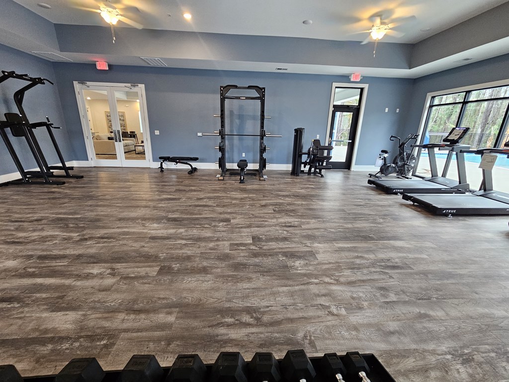 A gym with a variety of equipment including treadmills, weights, and exercise machines.