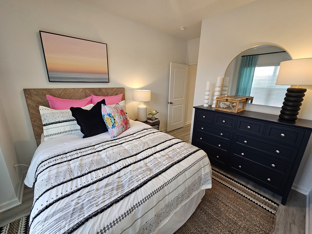 A bedroom with a large bed and a painting above it.