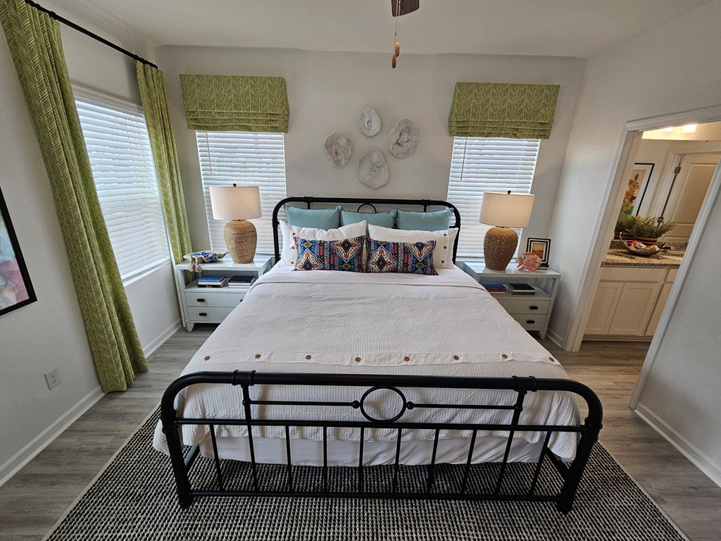 A bedroom with a large bed and a window with green curtains.
