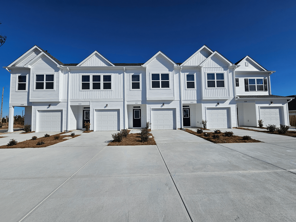 A row of white houses with a clear blue sky above them.