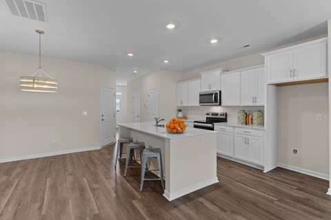 A kitchen with white cabinets and a wooden floor.