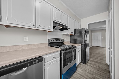 A kitchen with white cabinets and a black refrigerator.