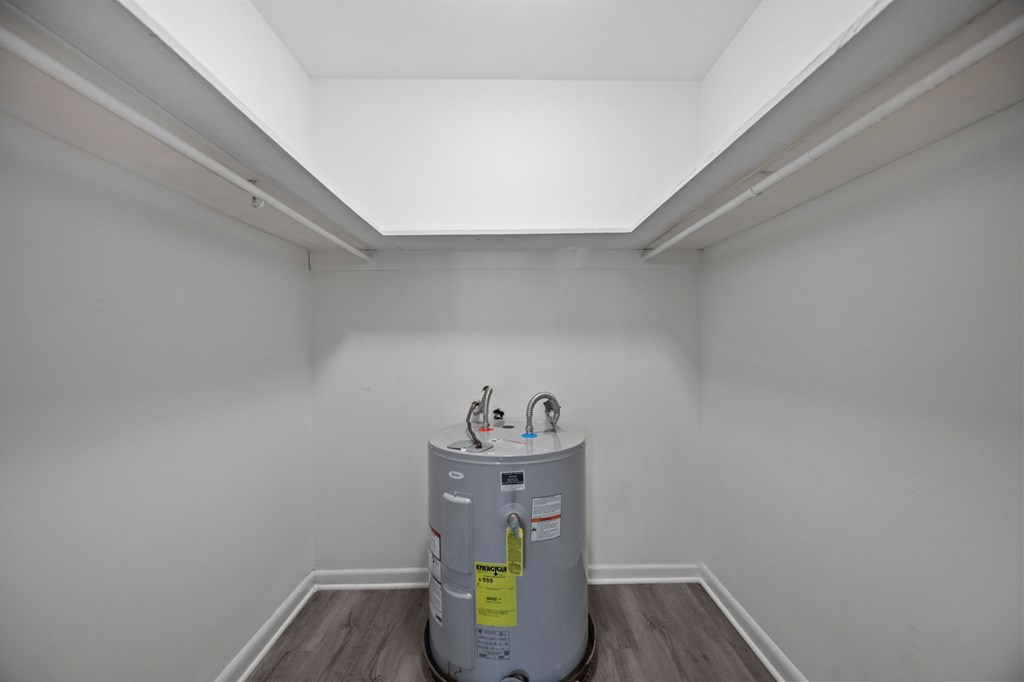 A water heater is in the corner of a room.