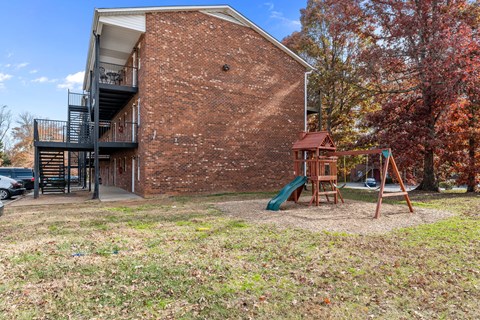 A red brick building with a playground in front.