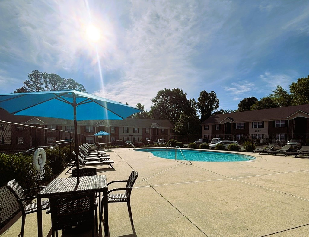 A sunny day at the poolside with tables and chairs.
