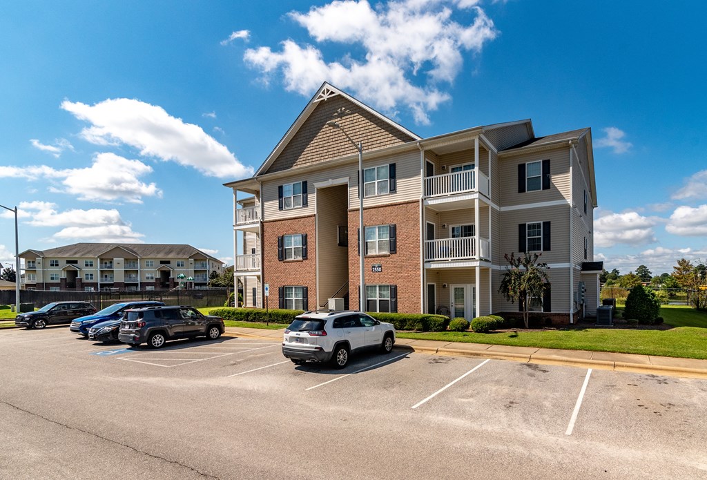 a large apartment building with cars parked in a parking lot