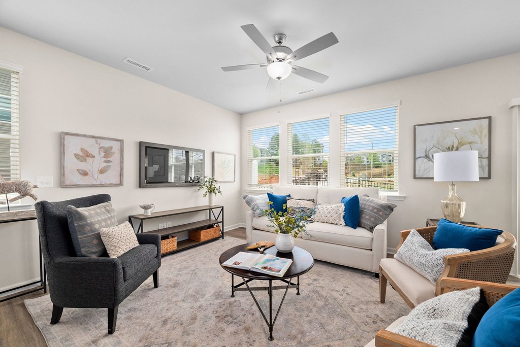 a living room with couches and chairs and a ceiling fan