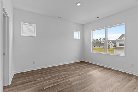 A room with wooden flooring and two windows.