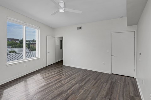 A room with a ceiling fan and a window overlooking a building.