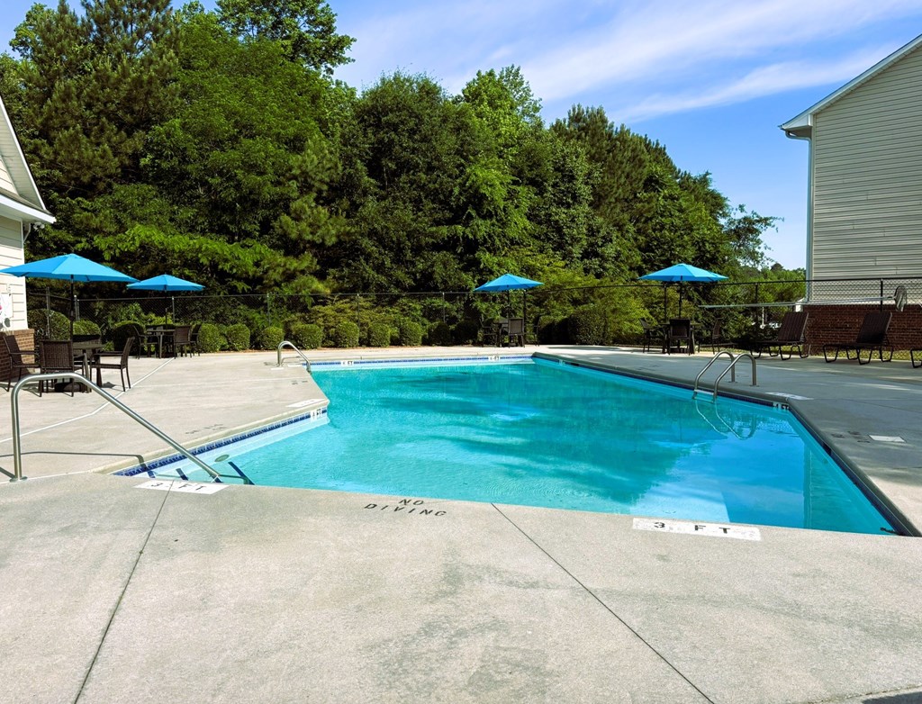 A swimming pool surrounded by trees and a house.