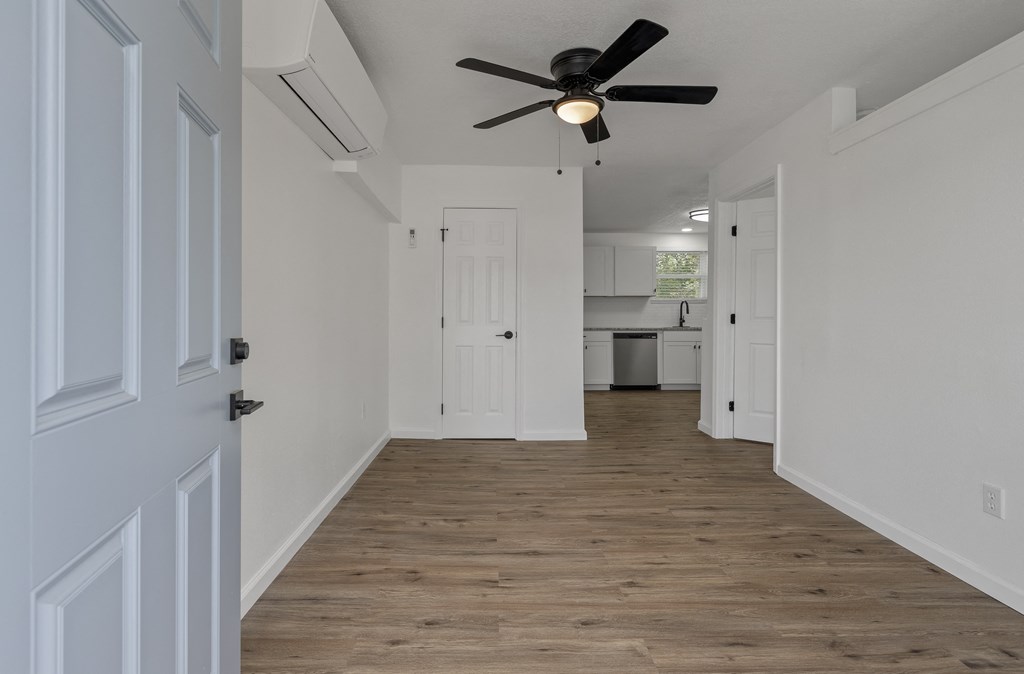 an empty living room with a ceiling fan and a kitchen