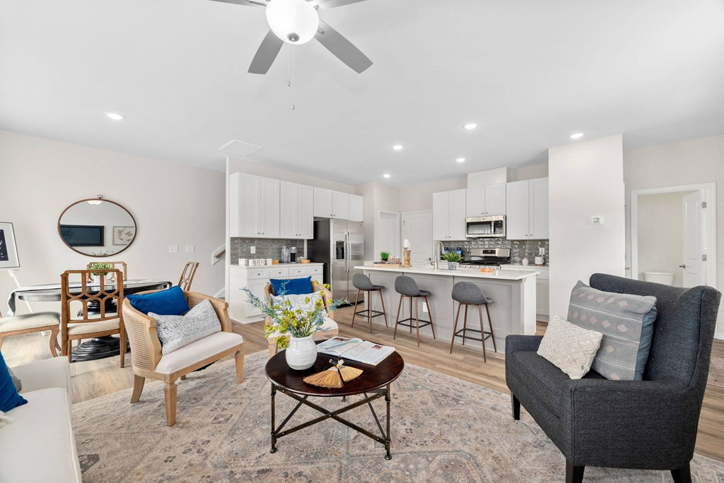 a living room with a kitchen and a ceiling fan