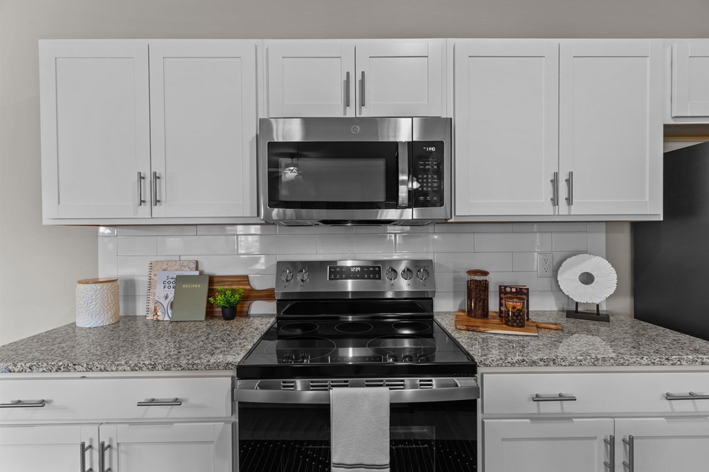 A modern kitchen with a stove, microwave, and cabinets.