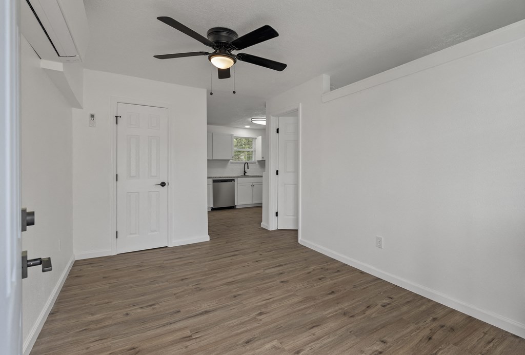 an empty living room with a ceiling fan and a kitchen