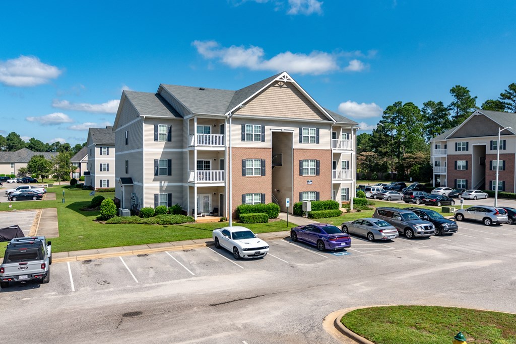 an apartment building with cars parked in a parking lot