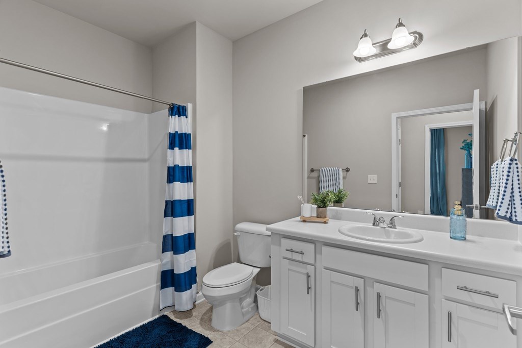 A white bathroom with a blue and white striped shower curtain.