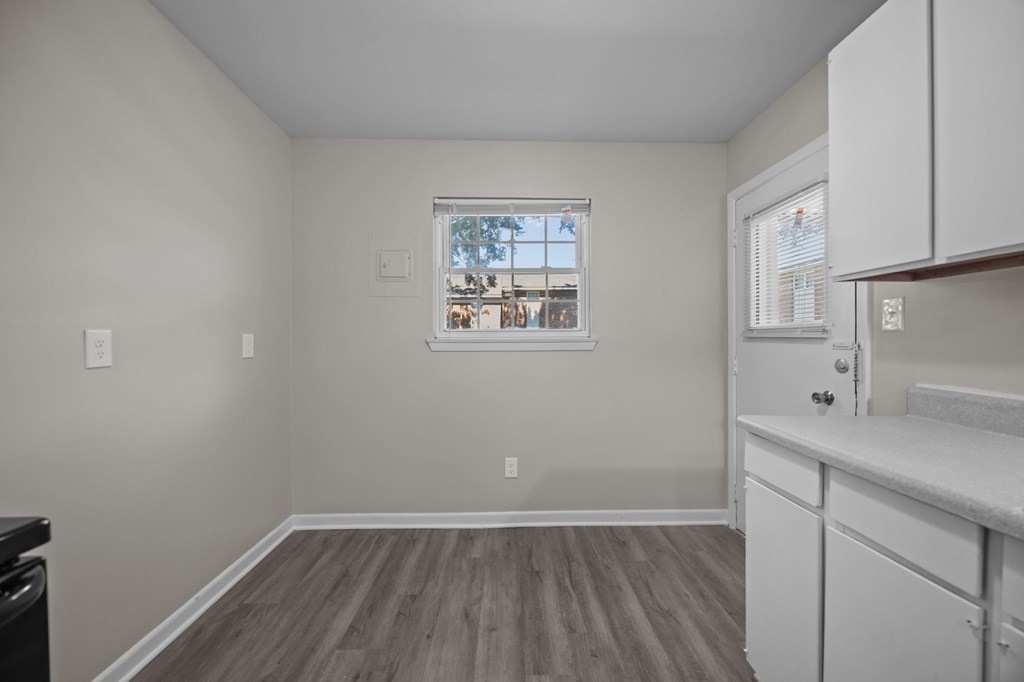 A kitchen with white cabinets and a window with a view of a cityscape.
