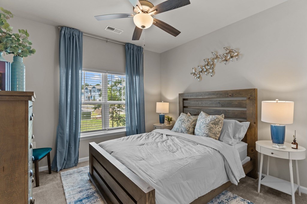 A bedroom with a bed, nightstand, and a window with blue curtains.