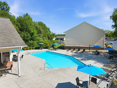 A pool area with a blue pool and a white building.
