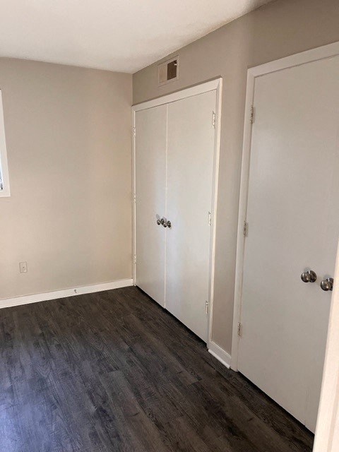 an empty room with white doors and a wooden floor