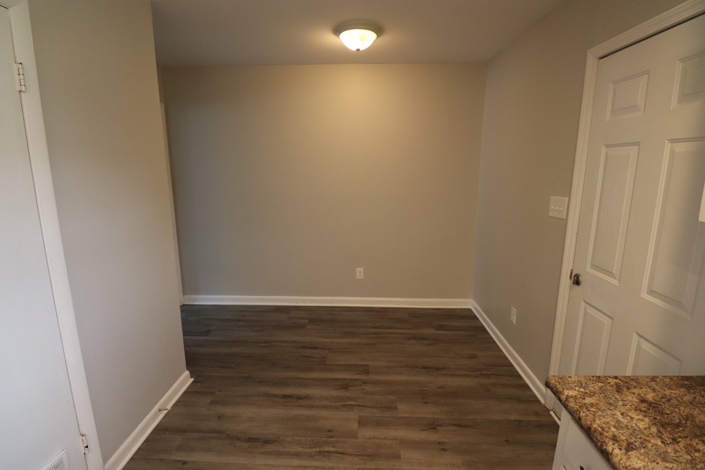 A room with wooden flooring and a door on the right.