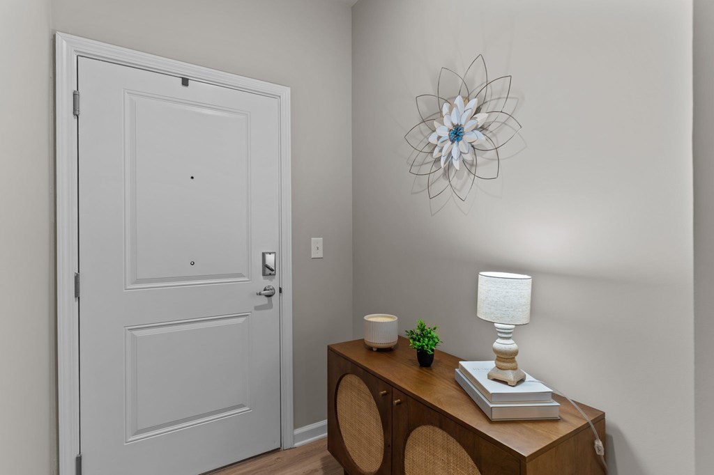 A white door is in a room with a wooden table with a lamp and a book on it.