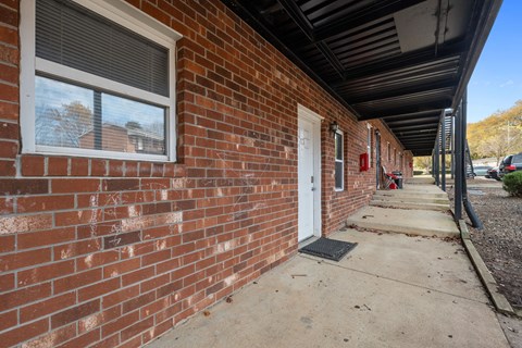 A red brick building with a white door and a window.