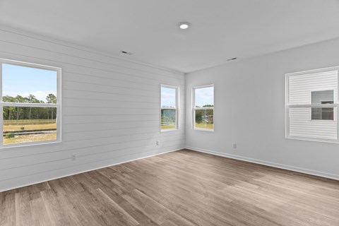 A room with wooden floors and white walls with two windows.