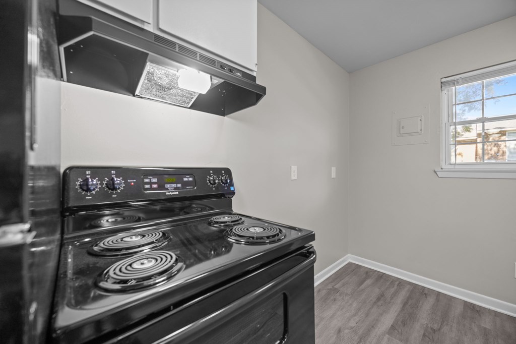 A black stove in a kitchen with a window.